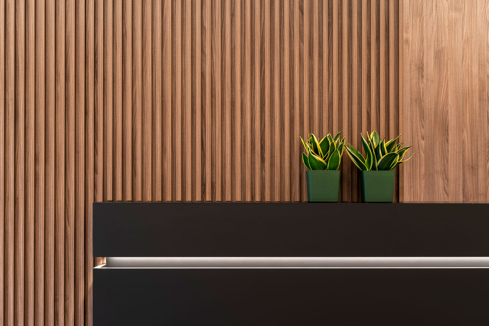 Bancone reception in Fenix nero e boiserie in noce canaletto